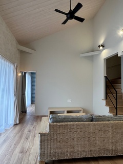 天井が高く開放感あふれるリビング。木材の床が温かみを感じさせ、シンプルなインテリアが落ち着いた雰囲気を醸し出している。