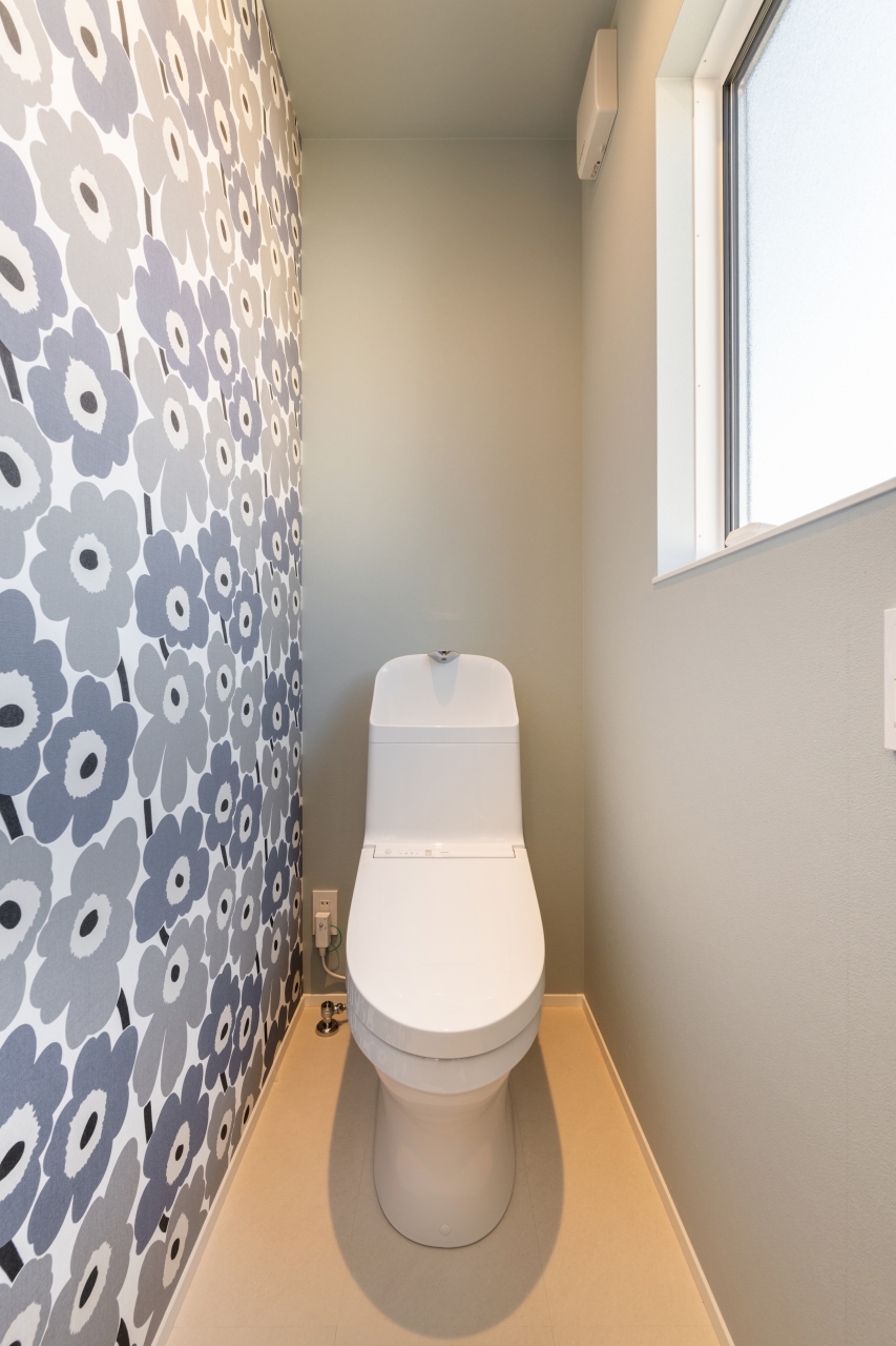 サンジョーホーム｜シンプルで清潔感のあるトイレ空間。窓からの自然光が明るさを演出し、アクセントクロスのマリメッコが個性的な印象を与えている。