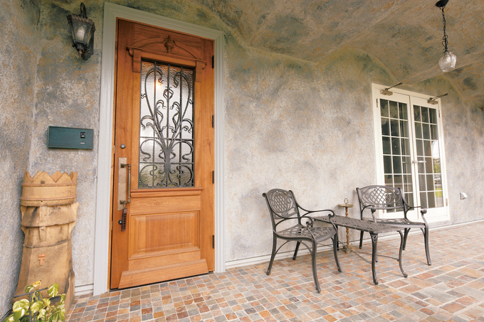 石張りのインナーテラスから玄関へ。アーチの天井で洞窟のようなイメージに仕上げた。ユニークなポストはイギリスから仕入れたチムニー（煙突）の先端を加工したもの