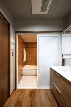 床材に合わせて、洗面台や建具、浴室のパネルまでトーンをそろえることで、空間全体に一体感が生まれた。