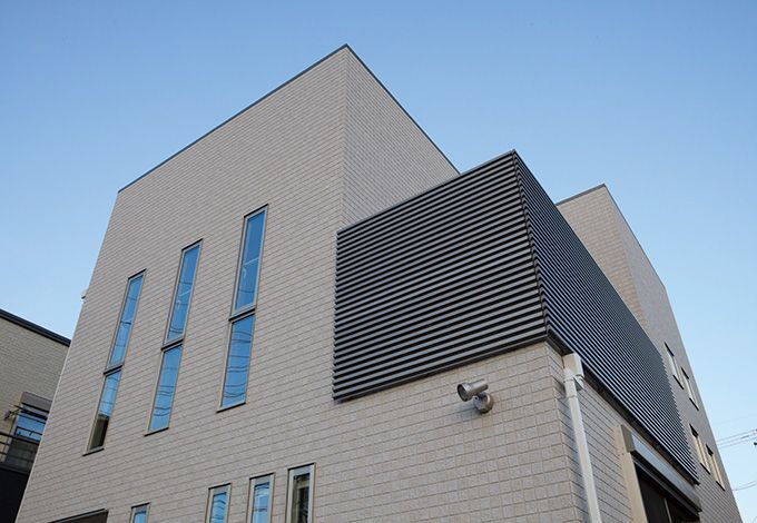 シャープなフォルムと窓のリズムで洗練を演出。横 格子のバルコニーがさらに印象を引き締める