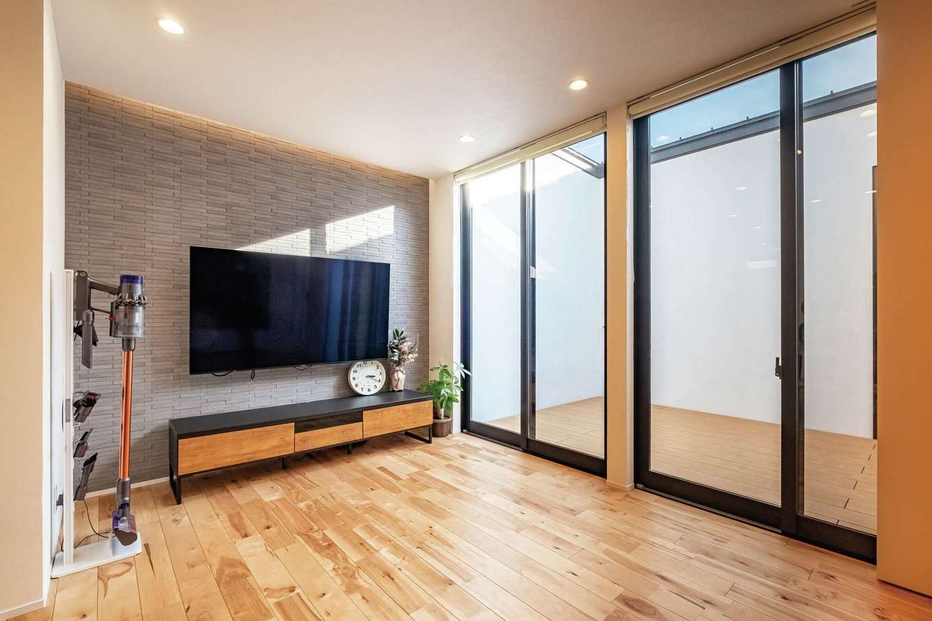 ARCHITECT STUDIO TEGOKORO （遠藤建築店）【子育て、間取り、平屋】壁掛けテレビの背面はエコカラットを貼りつけアクセントに。より多くの光を取り込めるハイサッシは「パティエ」の標準仕様。取り付けたロールカーテンは上げていることが多いそう