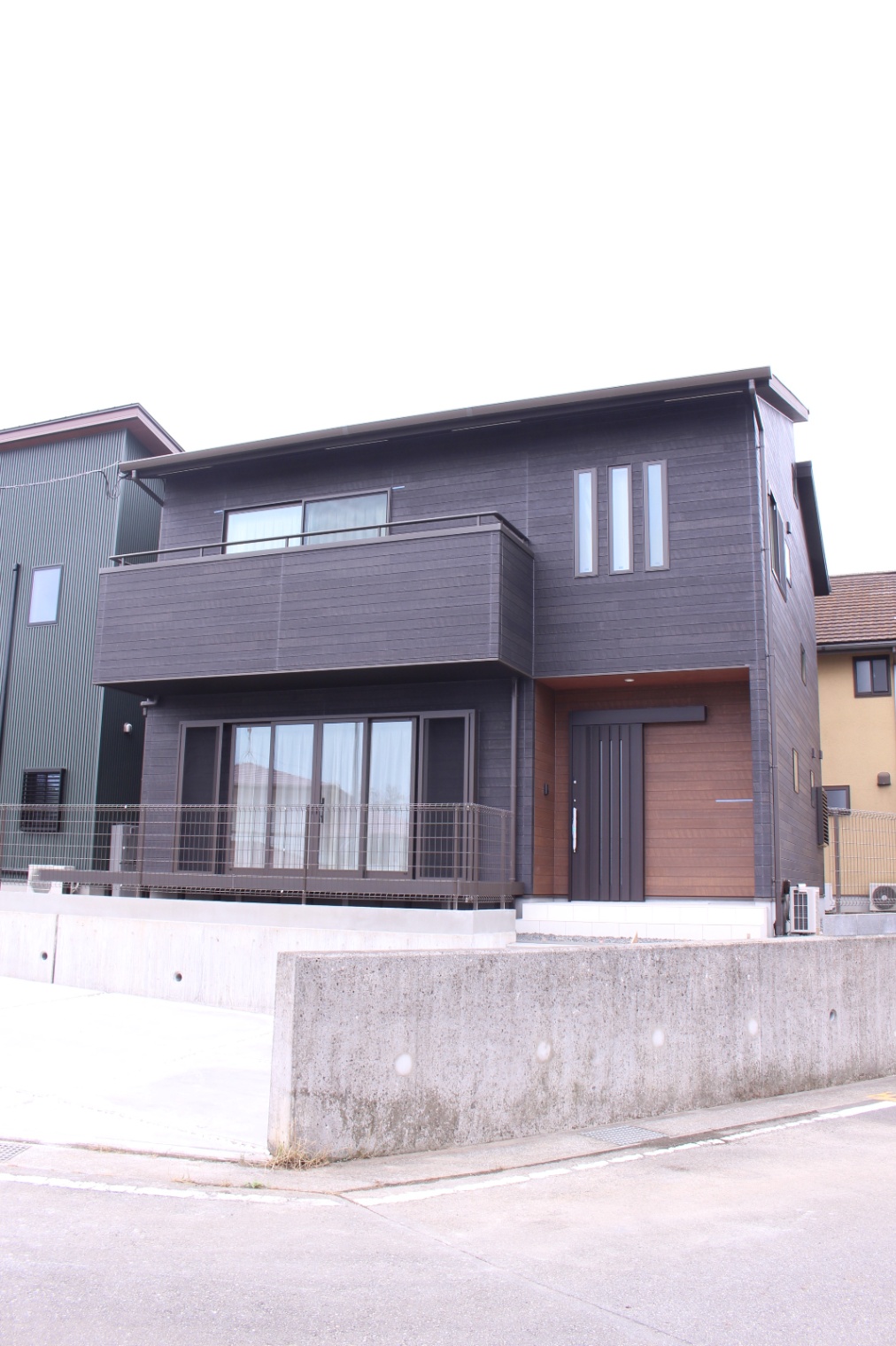 小野田産業～designers house project～｜モダンでシックな二階建て住宅の外観。シンプルながらスタイリッシュなデザインが目を引く。ウッドデッキがアクセントとなり、全体のバランスが見事に整っている。