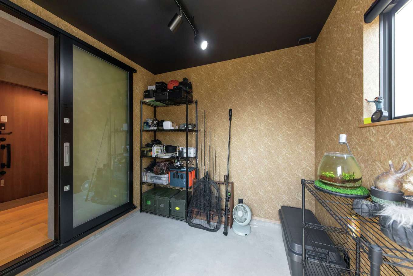 KUREKEN HAUS（榑林建設）【デザイン住宅、趣味、間取り】釣具やアウトドアアイテムが並ぶご主人の趣味部屋は、外からそのまま出入りできる土間仕様に。観葉植物やアウトドアチェアを置いて、くつろぎ時間を過ごすスペースにカスタマイズしていくそう