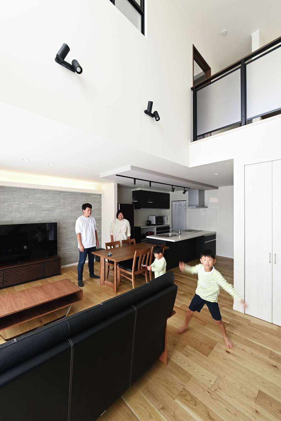 Yamaguchi Design 掛川店（アイフルホーム 掛川店）【デザイン住宅、子育て、間取り】ソファや階段の手すり、照明などに黒を用いてメリハリを効かせたシンプルモダンなLDK。子どもたちがのびのびと遊ぶ様子をどこからでも見守れる