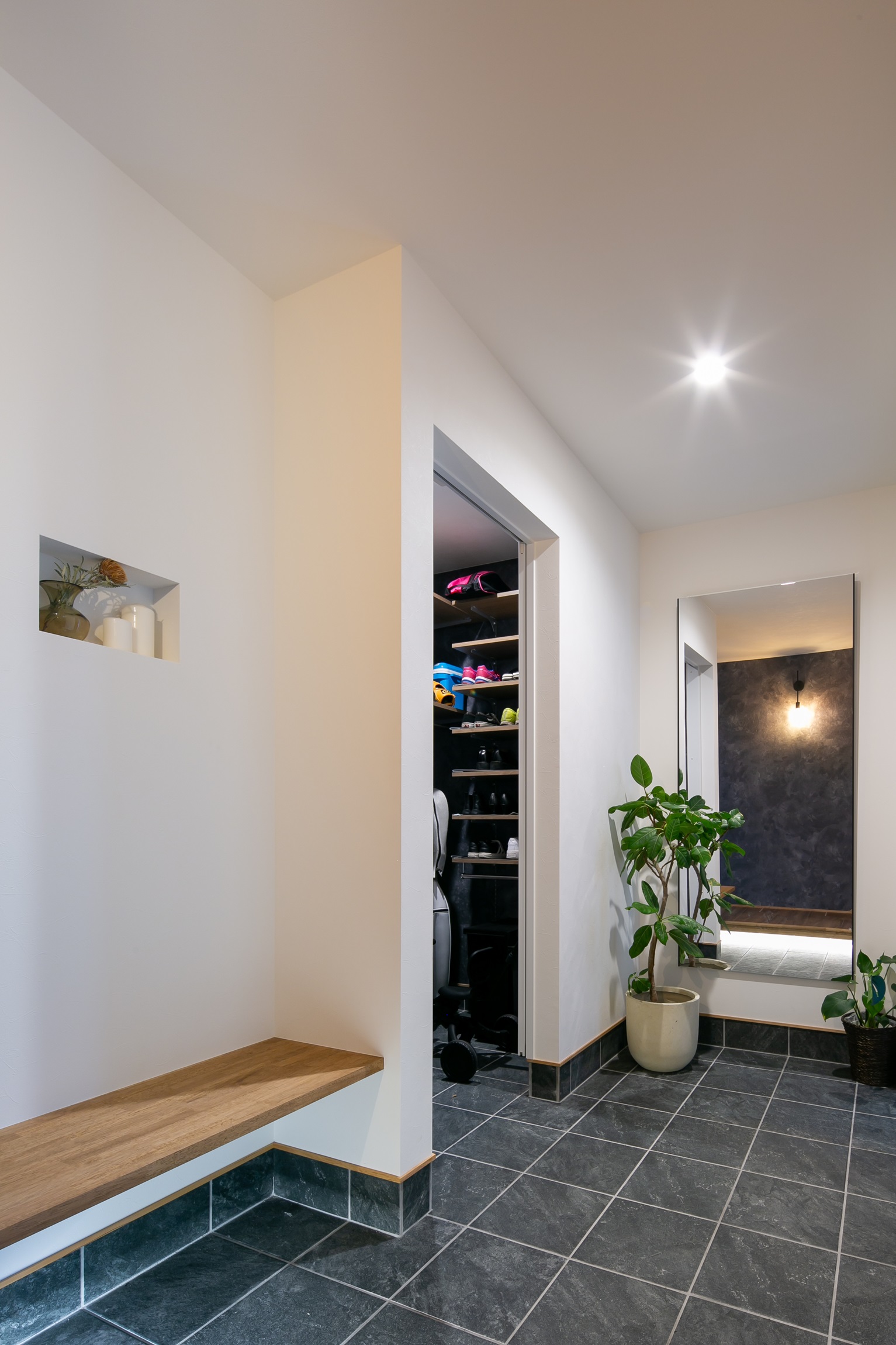 シンプル｜出掛ける前に玄関スペースで家族写真を撮りたい！との奥様からのご要望にお応えし、正面には鏡を設置。また、サイドには靴の履き替え・荷物を置くスペースとして活用できるベンチを施工。