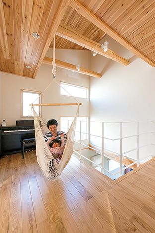 ひらおか建築【子育て、自然素材、建築家】ご主人がこっそり弾くピアノ や、ハンモックのある2 階ホー ルは、多目的スペースとして大 活躍。奥さまが展示会で見て 気に入った吹き抜けの梁も、 空間のアクセントに