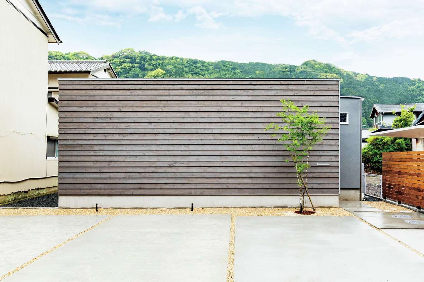 住家 JYUKA【デザイン住宅、間取り、平屋】外壁には耐候性に優れる塗り壁材「Sto」を使用。正面に採用された鎧張りのレッドシダーも、グレーで塗装してトーンをそろえている。住まい手の個性をほどよく放ちながら、周囲の環境にもなじむ表情に仕上がった