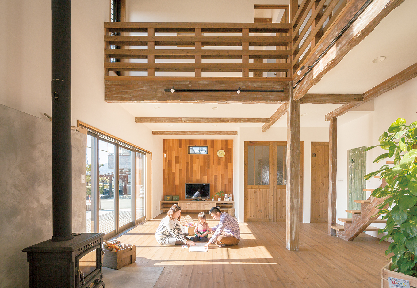 富士ホームズデザイン【デザイン住宅、子育て、インテリア】吹き抜けで2階とつながった開放的なリビング。奥の板壁は外壁と同じレッドシダーを色のバランスを見ながらランダムに張り合わせた。ドアもすべて『富士ホー ムズデザイン』のオリジナル