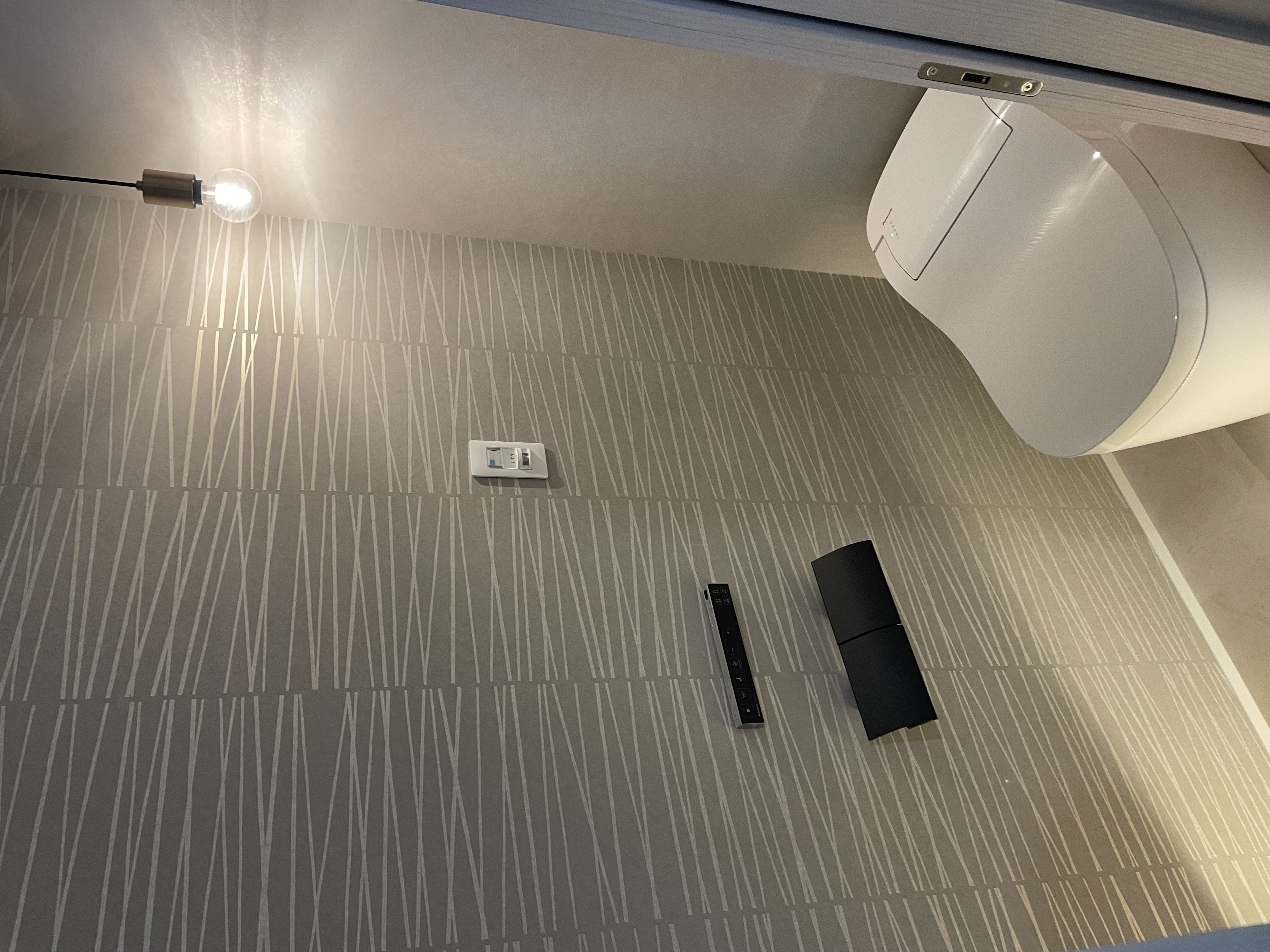 パナソニックホームズ中部第一支社 愛知第一支店・愛知第二支店｜シンプルでモダンなデザインのトイレ空間。壁面タイルが洗練された印象を与えており、落ち着いた雰囲気を演出している。