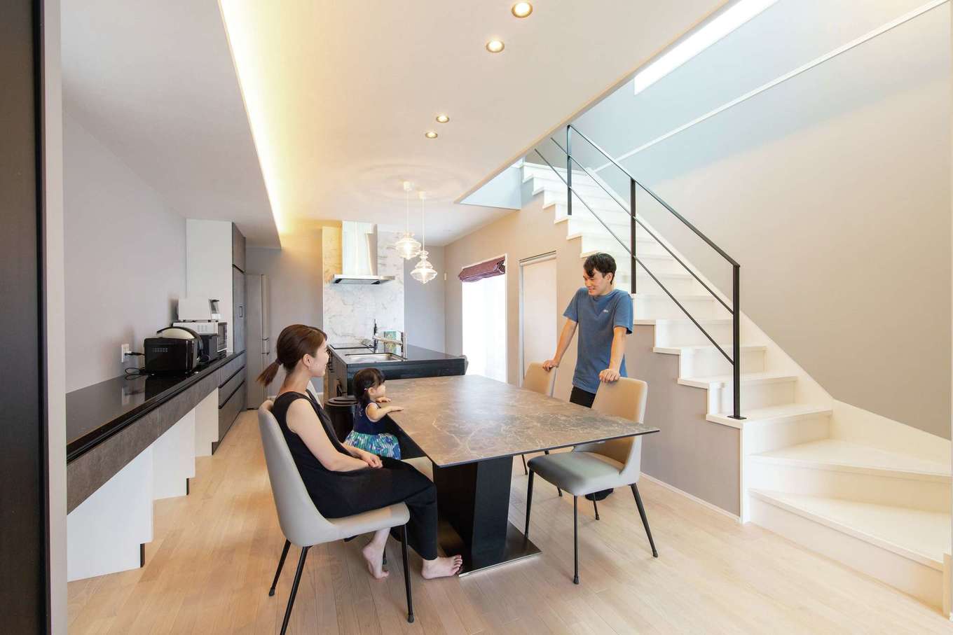 遠州鉄道 遠鉄ホーム【デザイン住宅、狭小住宅、インテリア】吹き抜けのある天井や間接照明、リビング階段が空間を広く演出。クリの無垢材の床にはミルキー塗装を施し、優しい肌触りとモノトーンの内装をコラボレートさせた。階段下やキッチン背面の収納が豊富で、無駄なものを見せず毎日すっきりと過ごせている