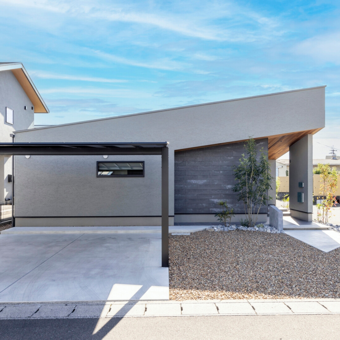 チェックハウス｜斬新な屋根デザインが特徴的な住宅の外観。ガレージ側からのアプローチもゆったりとした印象を与える。