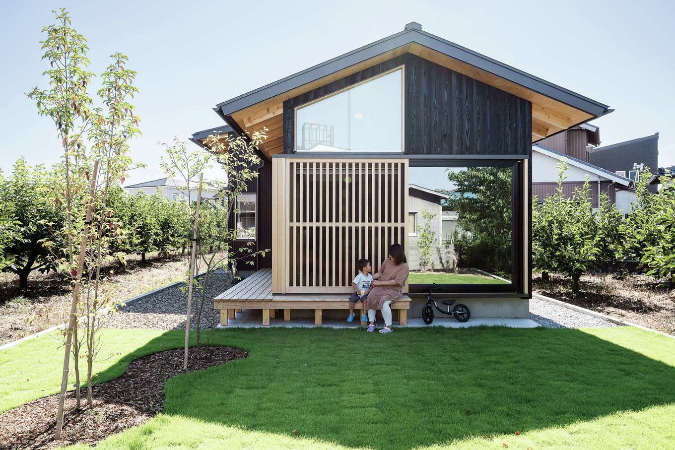 石牧建築【自然素材、間取り、平屋】敷地のいちばん奥から見た光景。大開口と格子のたたずまいが凛とした美しさを醸し出している。通り側からの視線を気にすることなく、広いプライベートガーデンでBBQや子どもプールなどを目一杯楽しめる。自慢の我が家に友達をたくさん呼んで、庭でくつろげる日を心待ちにしているそう