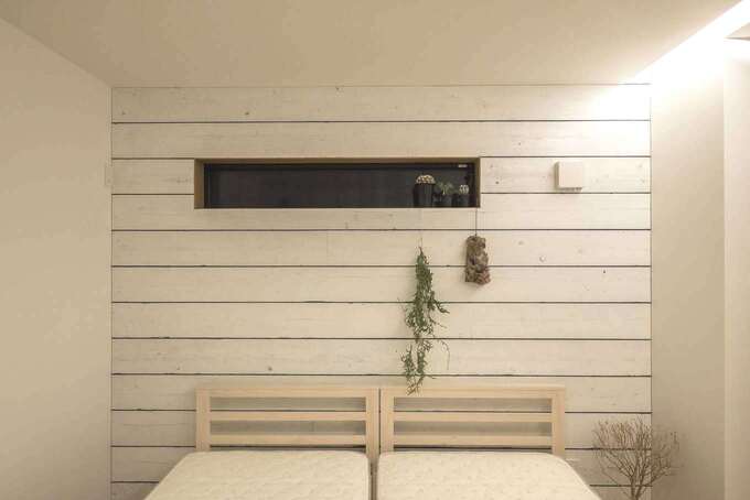 足場板は施主さんが塗装。寝室は大好きなカリフォルニアテイストで爽やかに仕上げた。プライバシーを守れるスリット窓で採光と通風を確保。夜は間接照明が優しいくつろぎに空間に