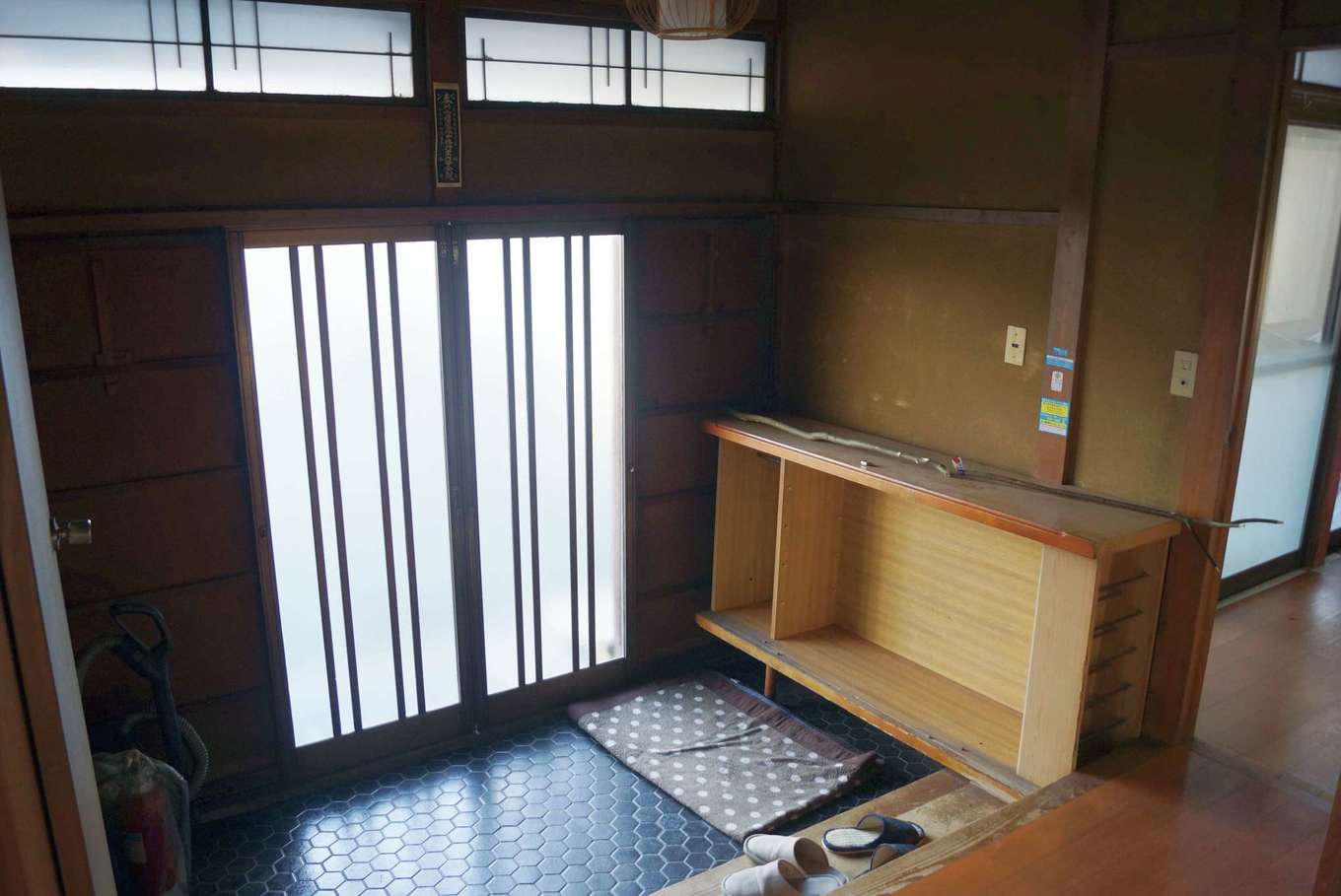 玄関は、アルミサッシの引き戸が取り付けられ、デザイン的な古さが気になる空間だった。高窓があるが天井は低く閉塞的で収納も不足。大きなシューズボックスとモダンな空間への変更を希望