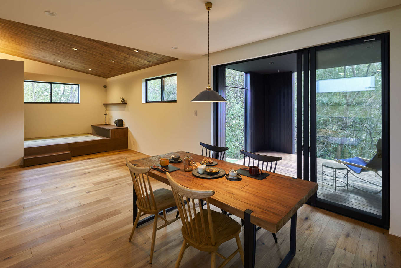 温戸ライフ【デザイン住宅、趣味、自然素材】COOLとモダンが共鳴する大人カッコイイLDK。3方向にグリーンの景色が広がり、どこにいても癒やされる。長く軒を伸ばしたウッドデッキが家の外と中をつなぎ、自然との一体感が心地いい