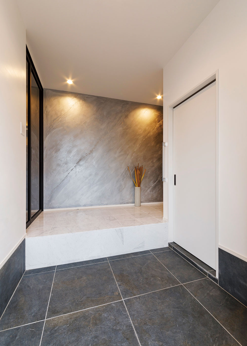 nattoku住宅｜かまちに大理石を採用して高級感を演出したエントランスホール。正面の壁にはアート作品のように美しいイタリア漆喰の「ユーロスタッコ」を採用。右側の扉を開けるとシューズクローゼット