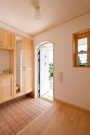 収納、鏡、カウンターと、必要なものを必要なサイズで用意。それらを明るい色調でまとめ、限られたスペースながら大らかさが漂う空間となった。上部がRになった玄関ドアは外観のアクセントにもなっている 