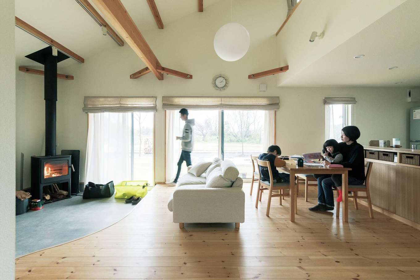 Casa（カーサ）【デザイン住宅、子育て、趣味】　「家に求めたのは、いつもみんなの息づかいを感じられること」と奥さま。ご主人が土間で作業をする間、子どもたちはリビングや和室でカードゲームをしたり、けん玉を練習したり、お絵かきをしたり。2人が喧嘩を始めると、ご主人が手を止めて仲裁に入り、いつの間にか笑い声がリビングに響く。そして再び気がつけば、Kさんは薪ストーブの様子を見ている。この空気感は、吹き抜けを通して2階のフリースペースまで巻き込み、全体を一つの空間に仕立てる。いつも近くに家族の気配があるのが心地いい。