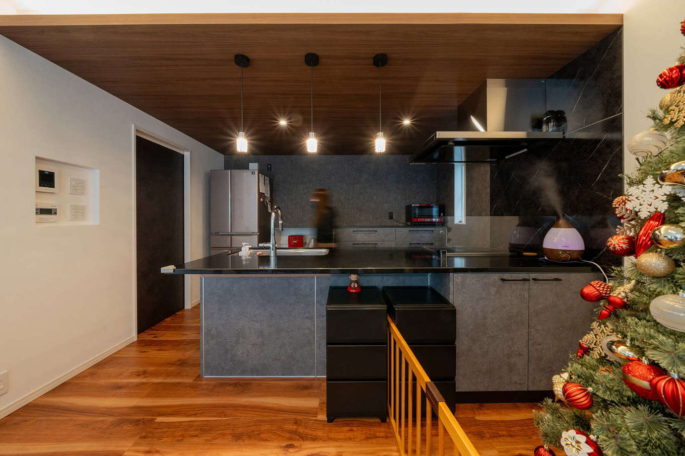 遠州鉄道 遠鉄ホーム【デザイン住宅、子育て、ペット】グレーのキッチンと濃い木目の下がり壁がベストマッチなダイニングキッチン。キッチンに立っていると家じゅうを見渡せるので、家事をしながら子どもの様子を見守れる。また、玄関から水回りを通ってキッチンに行けるため、日常生活の移動も楽にできる