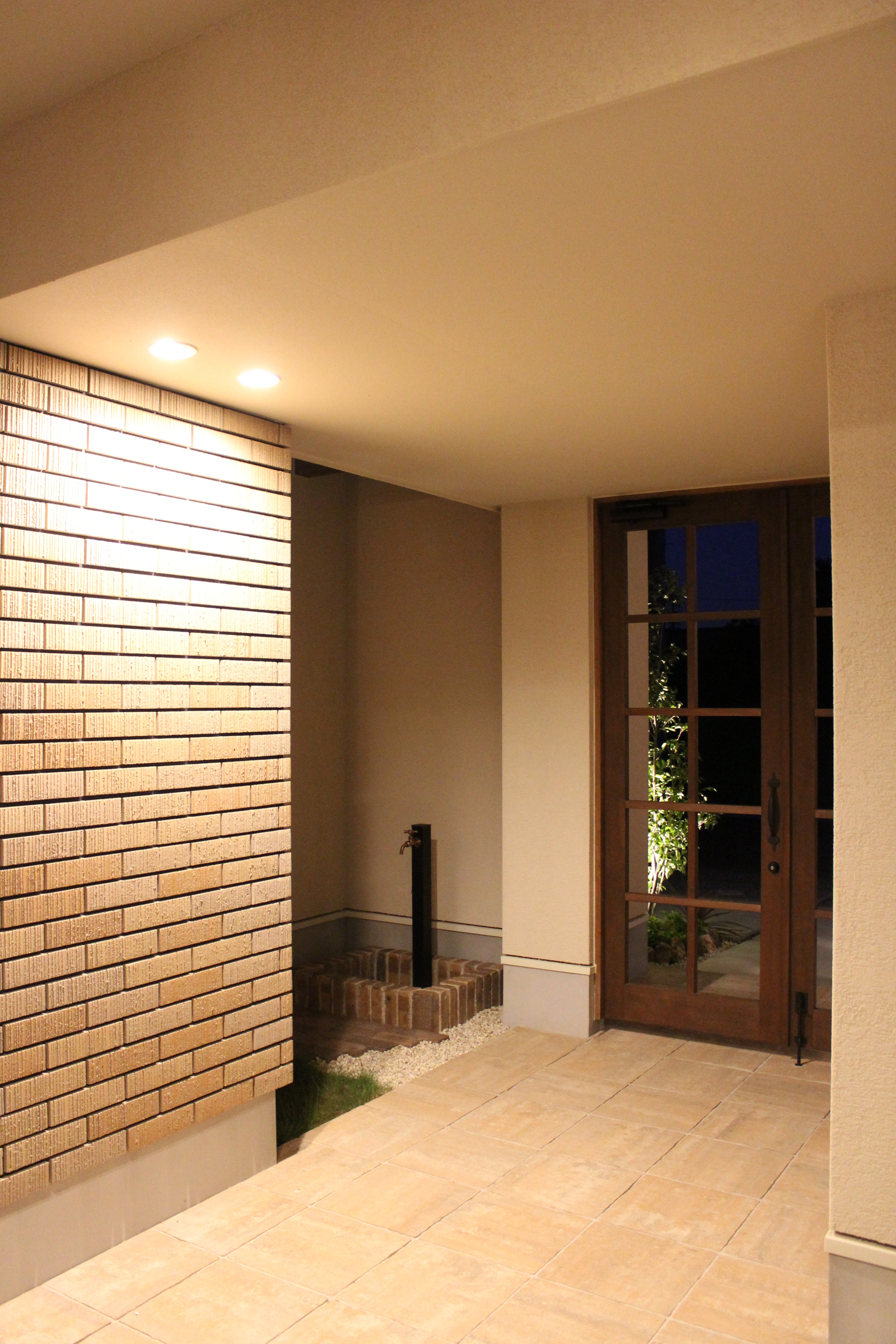 安田住宅｜安田建築設計室｜玄関ドアからアプローチを進み、門扉を開け外へと向かう。夜間にもやわらかい照明が訪れる人を迎え入れる。シンプルながらも洗練されたデザインが特徴的。