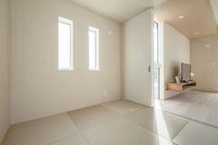 リビングとフラットに続く和室。友人や親戚が大勢集まる時にはリビングが拡張できる。畳の色はリビングのインテリアと調和するベージュ系に
