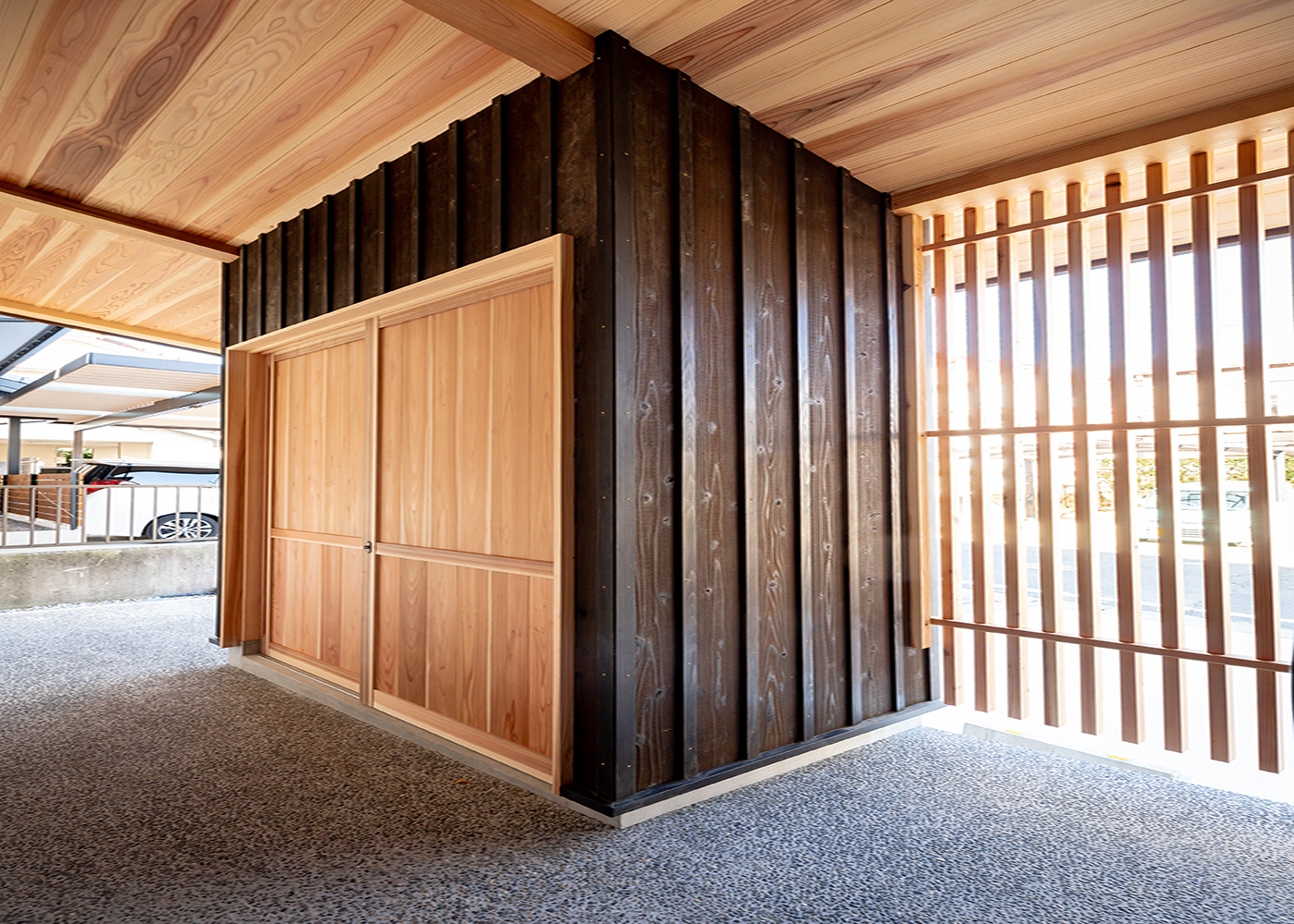 有吉住宅【趣味、自然素材、インテリア】格子塀の裏側に設けたアウトドアストッカーには、タイヤなども収納できる。センスのにじむ建具は、職人の手による造作