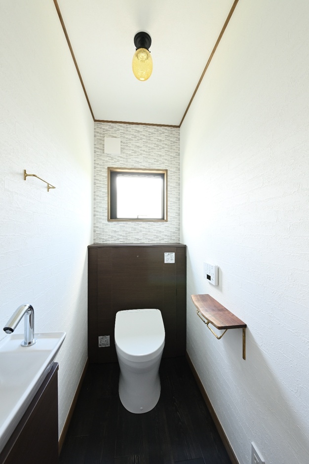 壁紙と床材で落ち着きを感じるトイレスペース。シンプルながら清潔感があり、窓から入る光で快適さを提供。