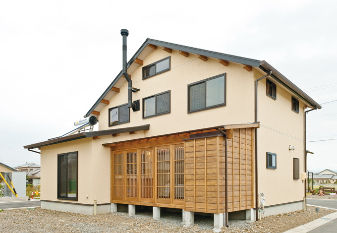 シンプルなフォルムながら、薪ストーブの煙突と板 張りのデッキが目を引く。屋根には太陽熱温水 器。風呂とキッチンの給湯が太陽エネルギーでま かなえる