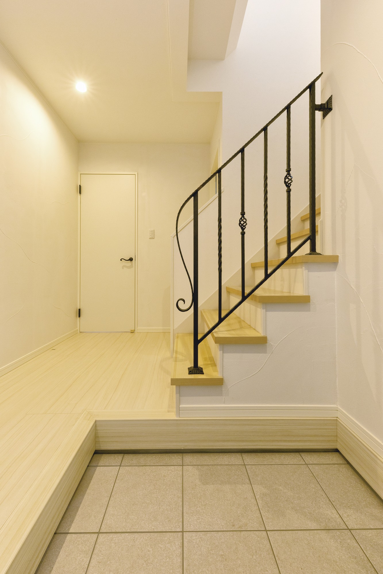 アヴィエスホーム｜明るく快適な玄関土間スペース。タイル張りの床とシンプルなデザインの階段手すりがアクセントとなっている
