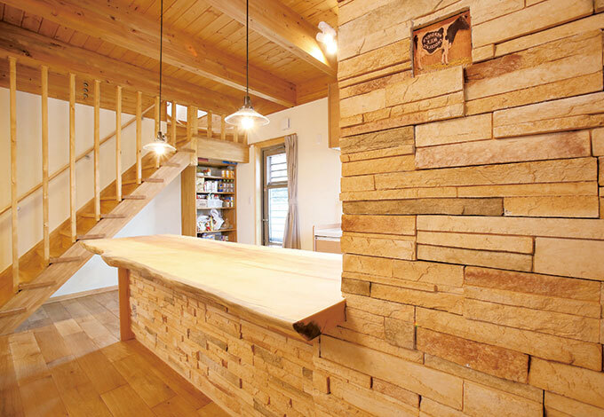 無垢板のカウンターが存在感を放つオープンキッチン。形や色の違うタイルを組み合わせた壁は、センス抜群の奥さまが手作業で貼った