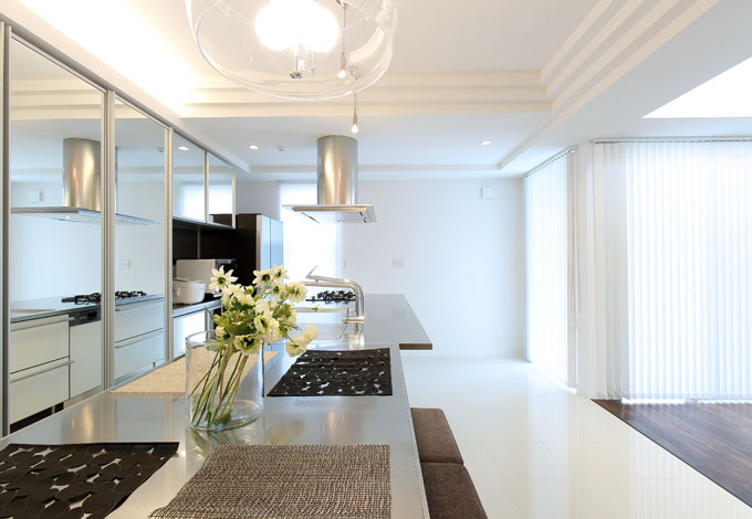 丸昇彦坂建設【デザイン住宅、間取り、ガレージ】キッチンと一列に配置したステンレスのダイニングテーブル。調理や盛り付けのスペースを広く確保でき、配膳や片づけも便利