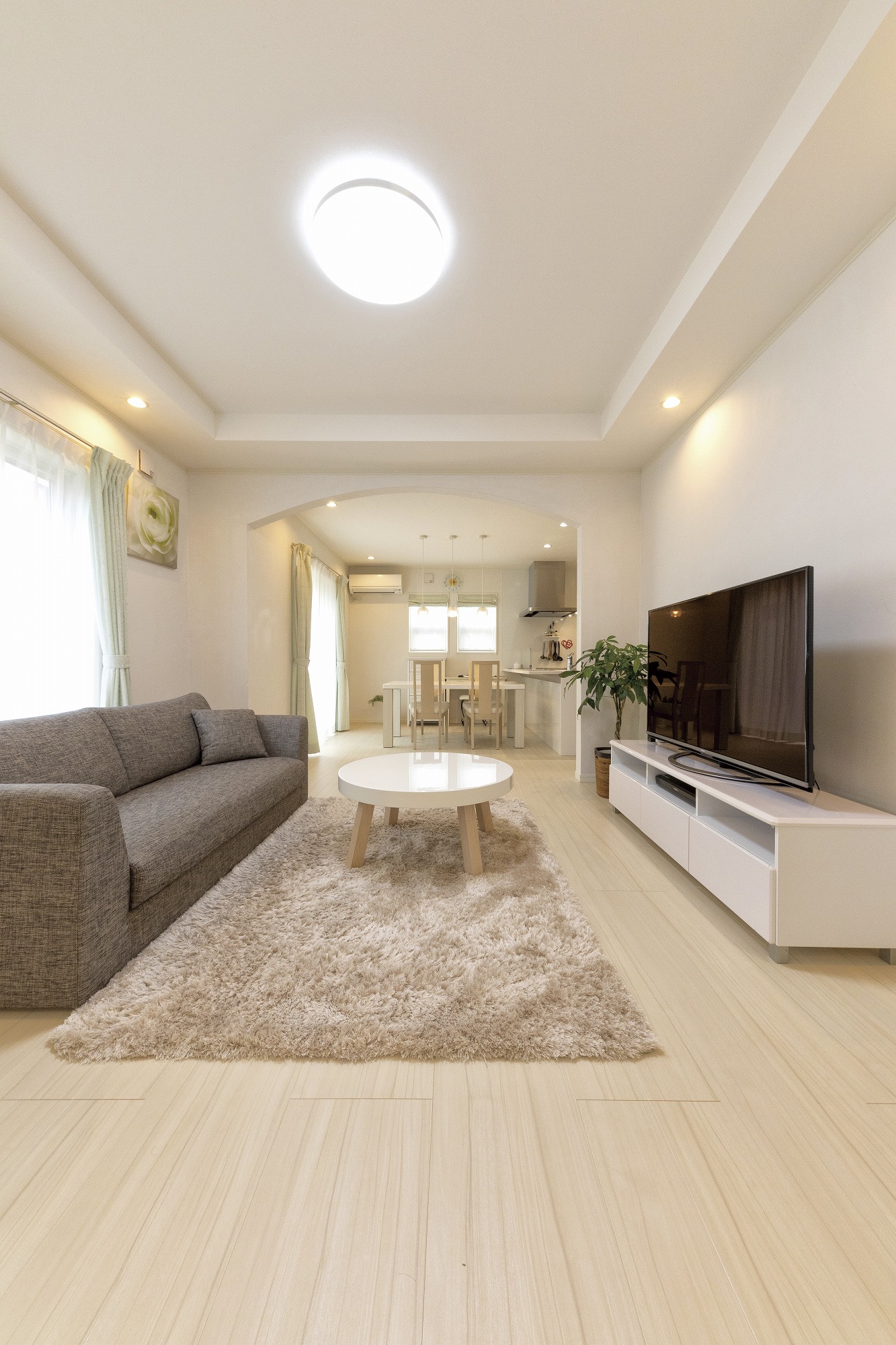 アヴィエスホーム｜広々としたリビングルーム。大きなカウチソファと白を基調としたインテリアがシンプルで洗練されている。