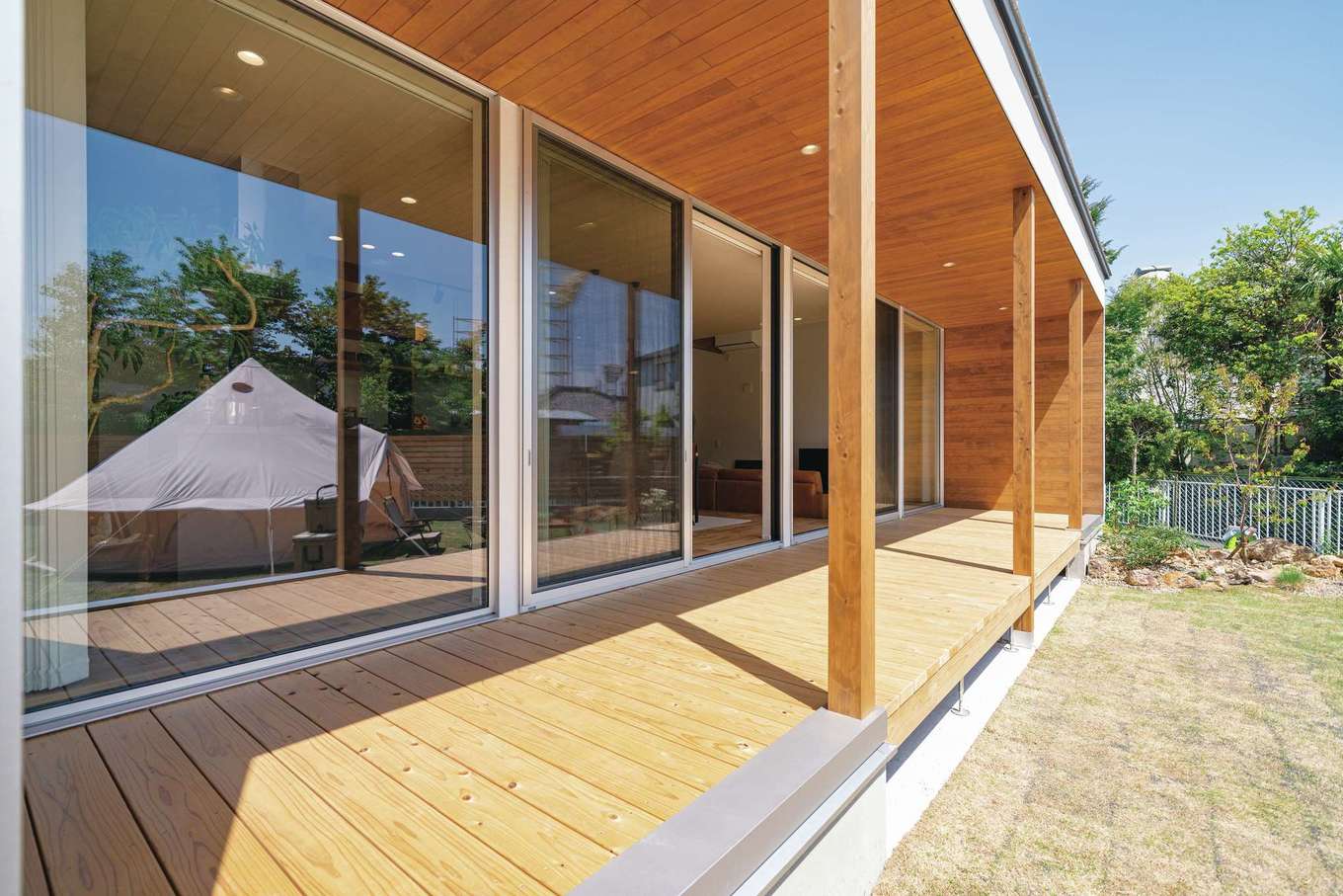 住家 JYUKA【デザイン住宅、間取り、建築家】庭に面して大胆な開口をもち、全面に渡されたウッドデッキ越しに光や風、開放感とともに、多彩な楽しさ、豊かさが室内に運ばれる