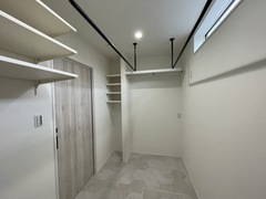 白を基調としたウォークインクローゼット。上部に棚があり、収納力が高く、小窓から自然光が入るため明るい空間になっている。