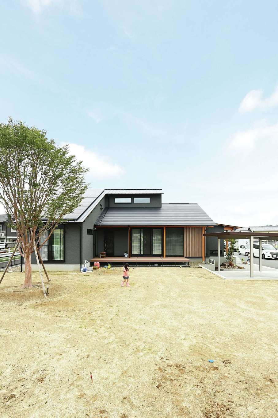 Yamaguchi Design 【自然素材、間取り、スキップフロア】大屋根の平屋風の外観。破風を取り払い、屋根のラインをスマートにデザイン。ウッドデッキはリビングと子ども室から直接出入りできるため、子どもたちがぐるぐる回ってのびのびと遊べる
