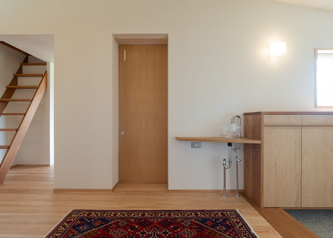 石牧建築【デザイン住宅、子育て、平屋】玄関の右手はトイレ用と感染予防対策の手洗いコーナーを設置。地元天竜の吹きガラス工芸作家・栗原瑠璃華さんが作った洗面ボウルが水を受け止めてくれる