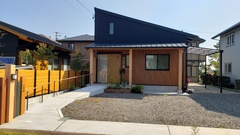 片流れ屋根が特徴的なシンプルモダンの外観デザイン。ウッドの外壁と黒い屋根のコントラストが洗練されており、周囲の自然環境に調和する。