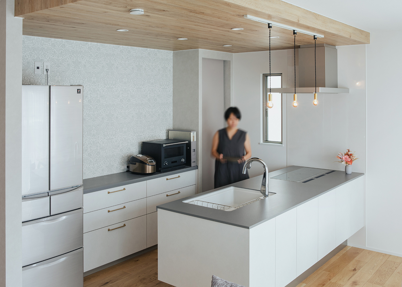 ナイスホーム【デザイン住宅、趣味、間取り】奥さまがこだわって選んだ「Panasonic」のキッチン。部屋のトーンに合わせて、ワークトップも食器棚もグレーに。木目の下がり天井がアクセントに