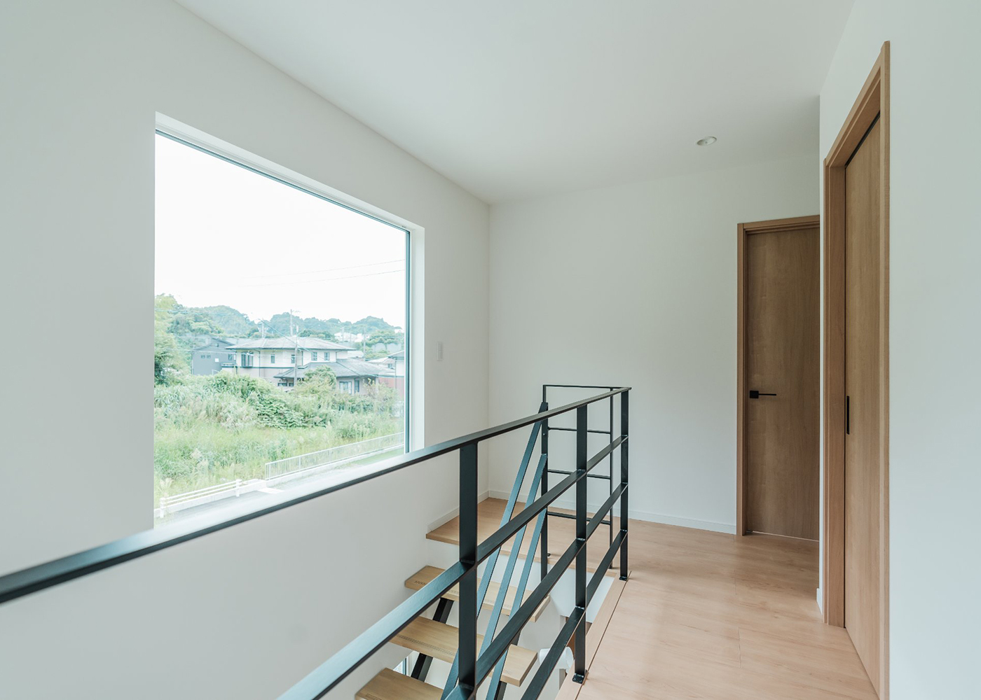 オレンジハウス【デザイン住宅、間取り、ペット】2階ホールから見える眺望はF邸の宝物。サロンのお客様もこの風景に癒やされながら施術室に入っていく。大きなFIX窓からの光が1階へとこぼれていく