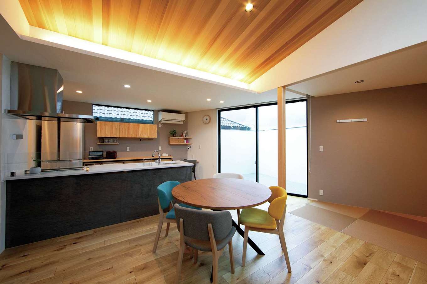 TENアーキテクツ 一級建築士事務所【デザイン住宅、子育て、建築家】三方を建物に囲まれた立地条件を考慮して、暮らしの中心となるLDKを2階に配置。バルコニーに高い外壁を備えたことで、外からの視線を遮りながら、光と風を取り込むことが可能に。勾配天井にレッドシダーを採用。間接照明の光で、ぬくもりのある空間を演出