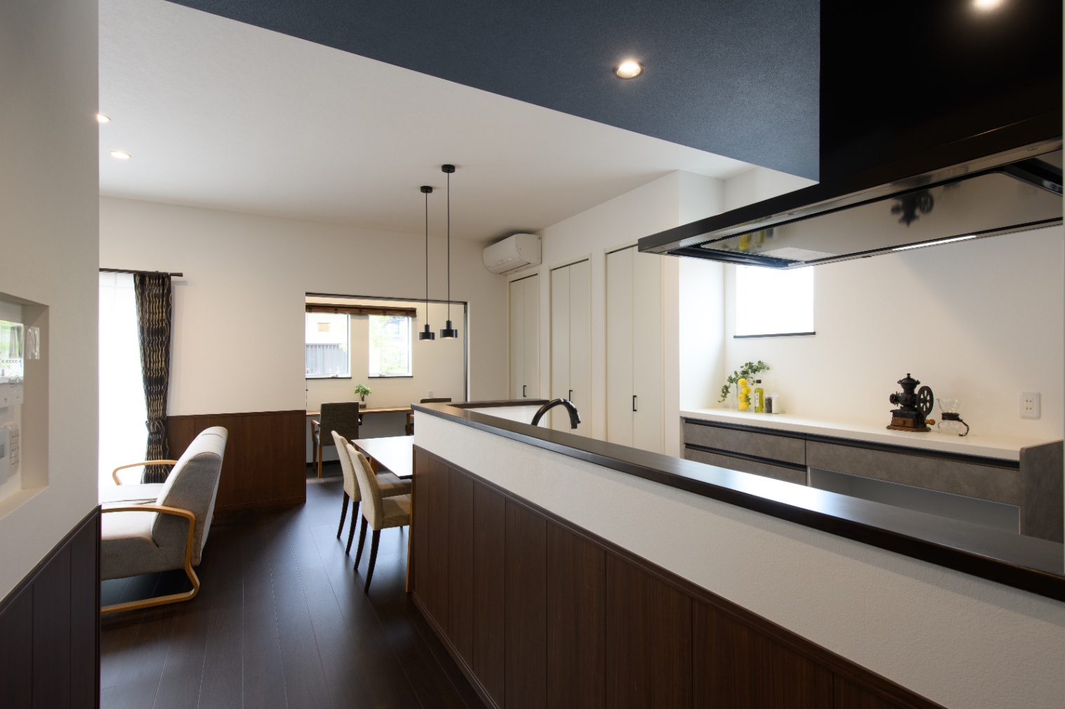 Sus∞Eco Home（サスエコホーム）｜キッチンからダイニングとリビングまで見渡せる開放的なLDK空間。落ち着いた色合いの木材が温もりを感じさせるデザインで、家族の団らんに最適。