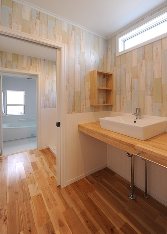 脱衣室と洗面室を離して、誰もがいつでも使いやすいよう配慮。造作の洗面台、腰壁、アクセントクロスを張ってアメリカンな雰囲気を演出