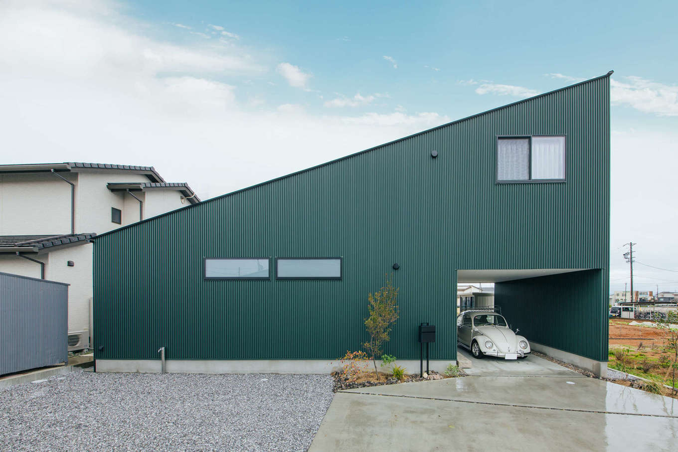 ハウスコネクト【デザイン住宅、建築家、ガレージ】大胆な片流れ屋根が印象的な外観デザイン。飽きのこないブルーグリーンの外壁が、のどかな田園風景に馴染んでいる