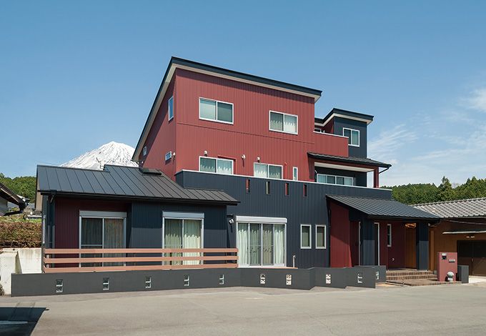 富士ホームズデザイン【デザイン住宅、輸入住宅、自然素材】赤と黒のツートンカラーをバランスよく配したガルバリウムの外観。モダン でありながら、どこか遊び心を感じさせ る外観が雄大な自然の中で存在感を放つ。外構も雰囲気に合わせて同社が手がけた