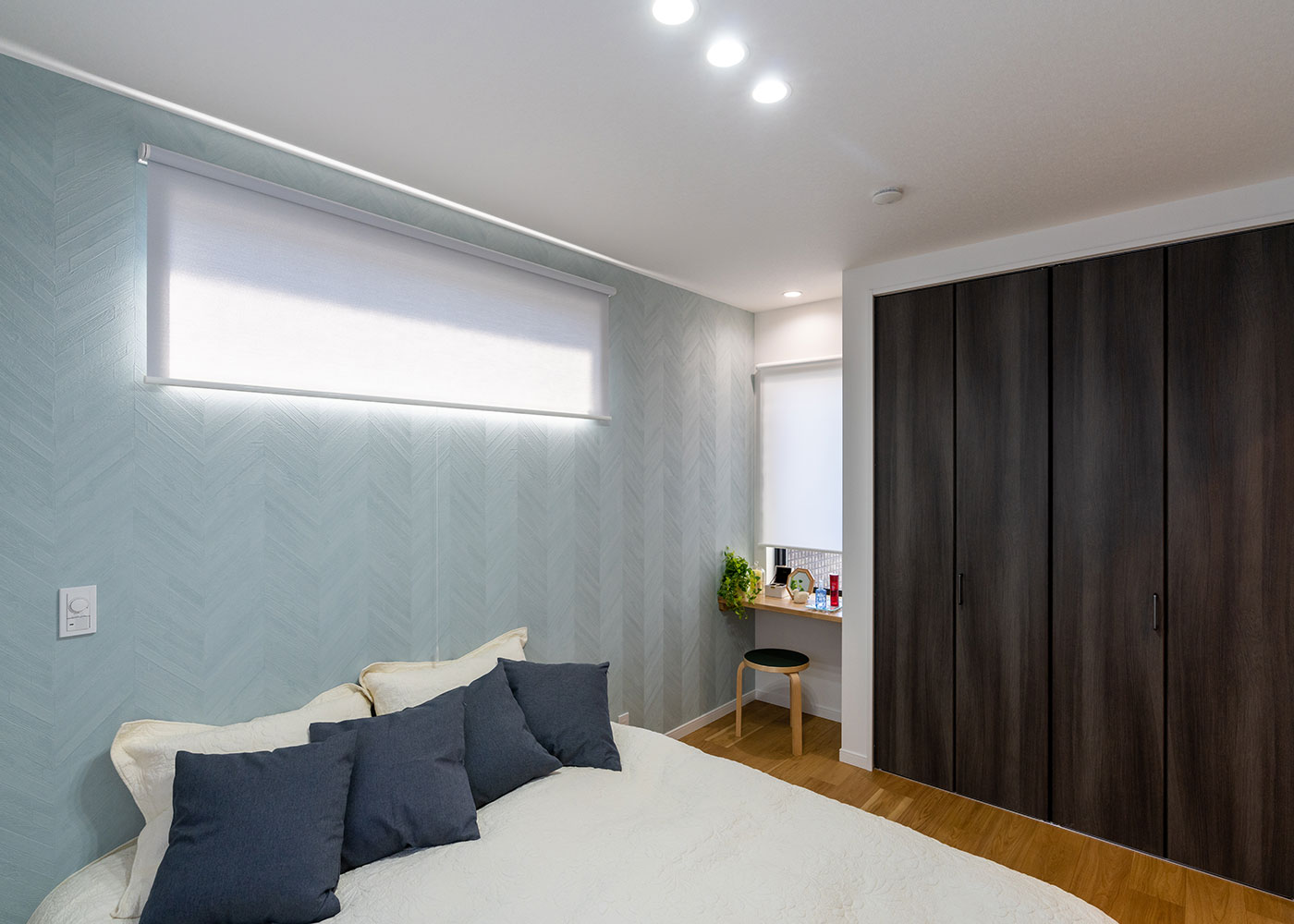 寺田工務店【収納力、狭小住宅、省エネ】主寝室の壁に青いヘリボーン柄のアクセントクロスを張って、爽やかな印象に仕上げた。窓際のデッドスペースを活かしてつくった空間は、ドレッサーにしたり、本やパソコンを置いたり、便利なスペースに