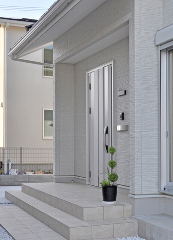 真っ白い玉砂利を敷き詰めたアプローチとシルバーの玄関ドアで、シンプルながらもセンスを感じさせるエントランス