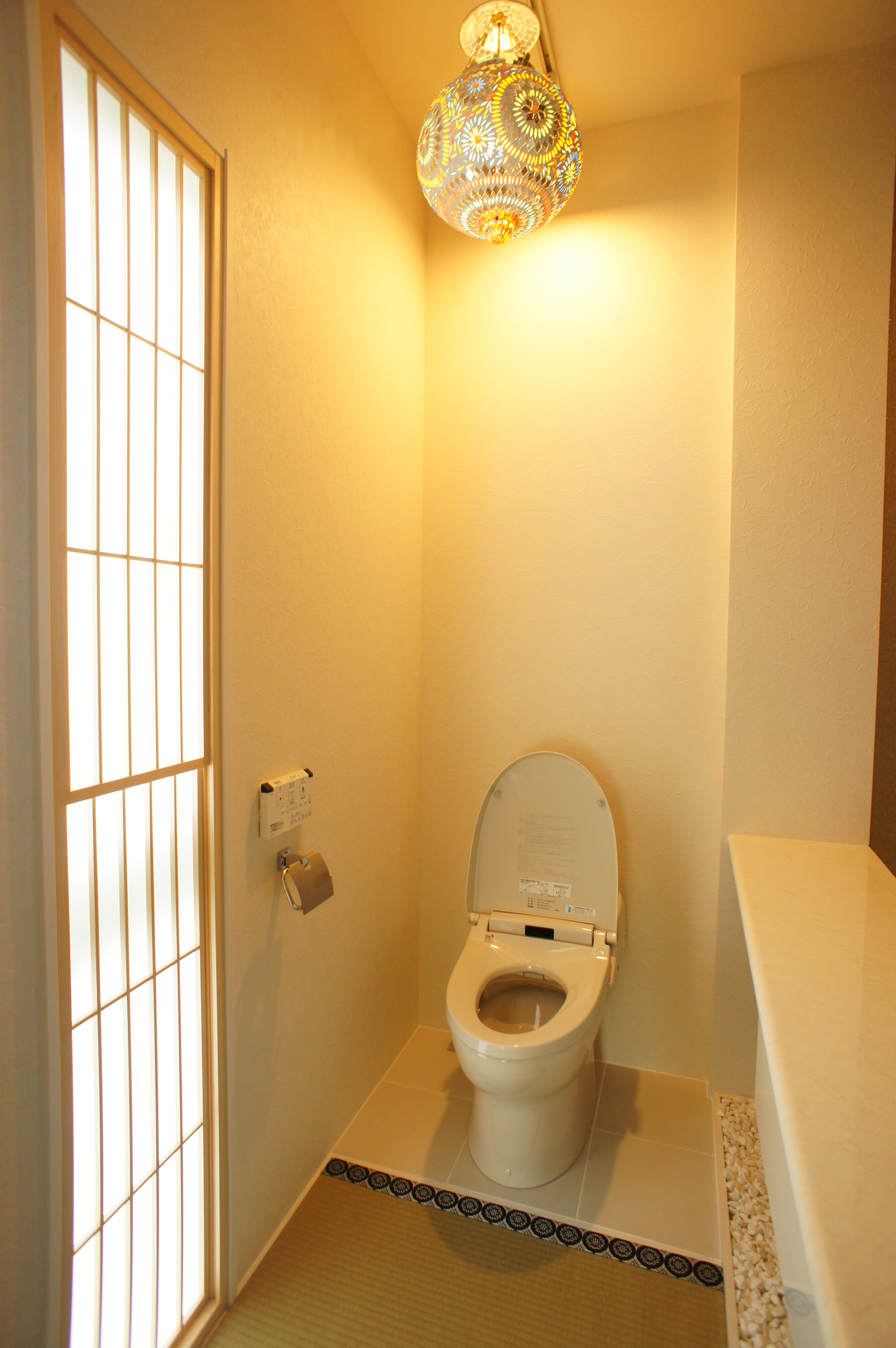 小野田産業～designers house project～｜和の趣を感じさせるトイレ空間。障子風の窓とこだわりの照明が、落ち着きと温かみを演出している。