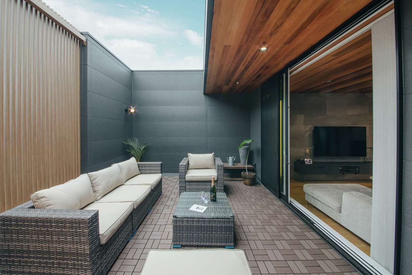 will建築工房【デザイン住宅、間取り、インテリア】レッドシダー張りの天井を軒天井まで延長し、リビングとの一体感を強調したバルコニー。ソファセットを置き、アウターリビングとして活用。壁を高くしてプライバシーを確保し、一部を格子仕様にして明るさを取り入れている