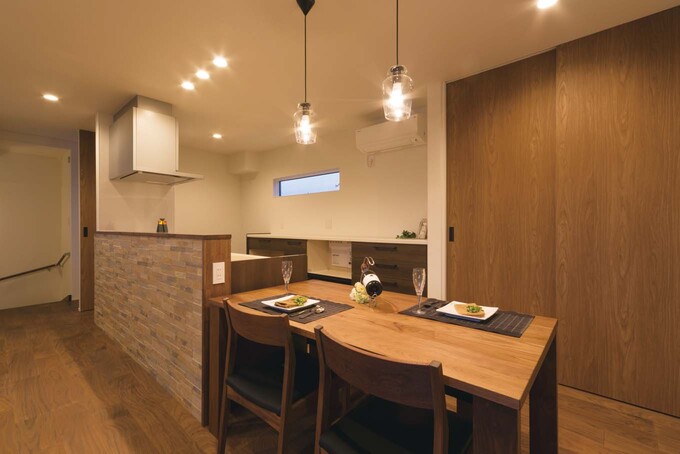 キッチンカウンターは落ち着いた色調のタイルで製作。ダイニング後ろにパントリー兼食器棚の大型収納を設けた